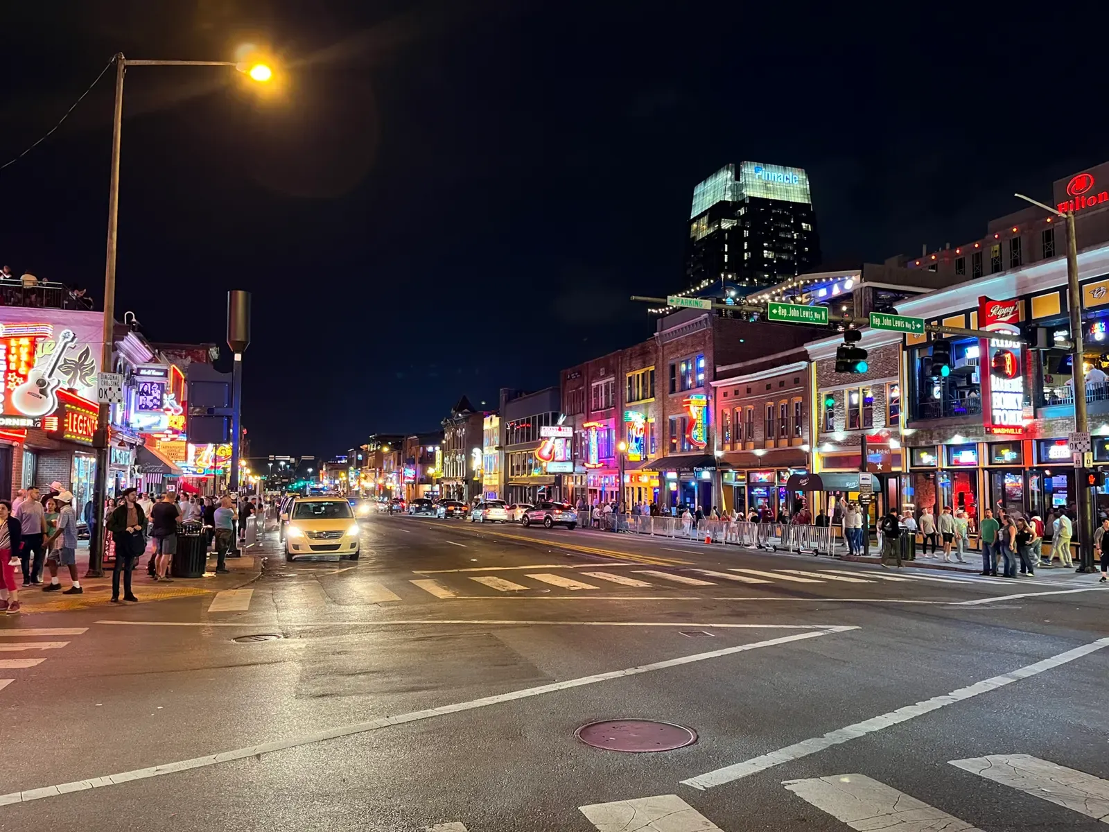 Crowds under lit neon signs on Lower Broadway in Nashville at night