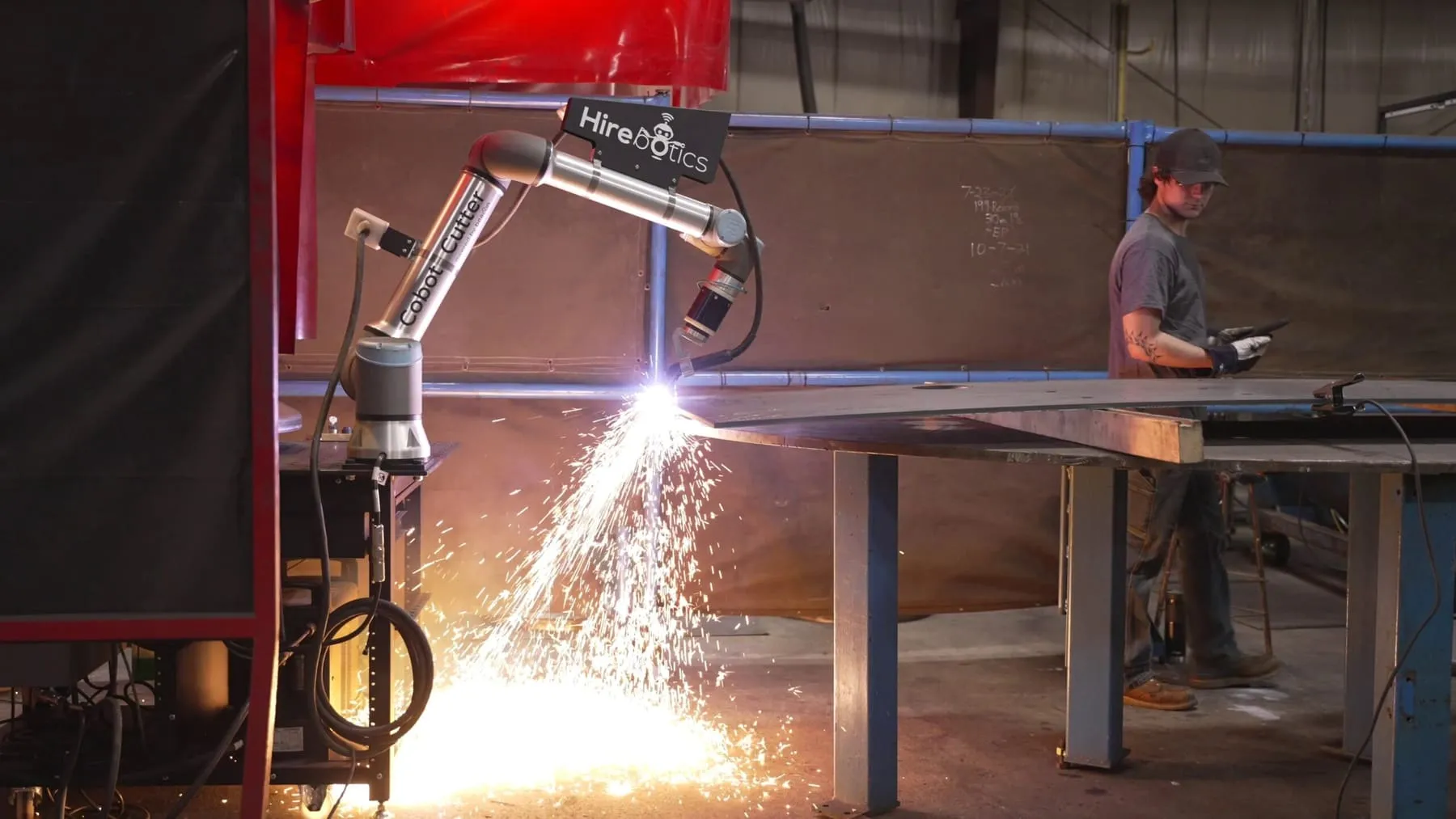 Cobot Cutter plasma cutting at Tank Technology while the operator monitors from his phone