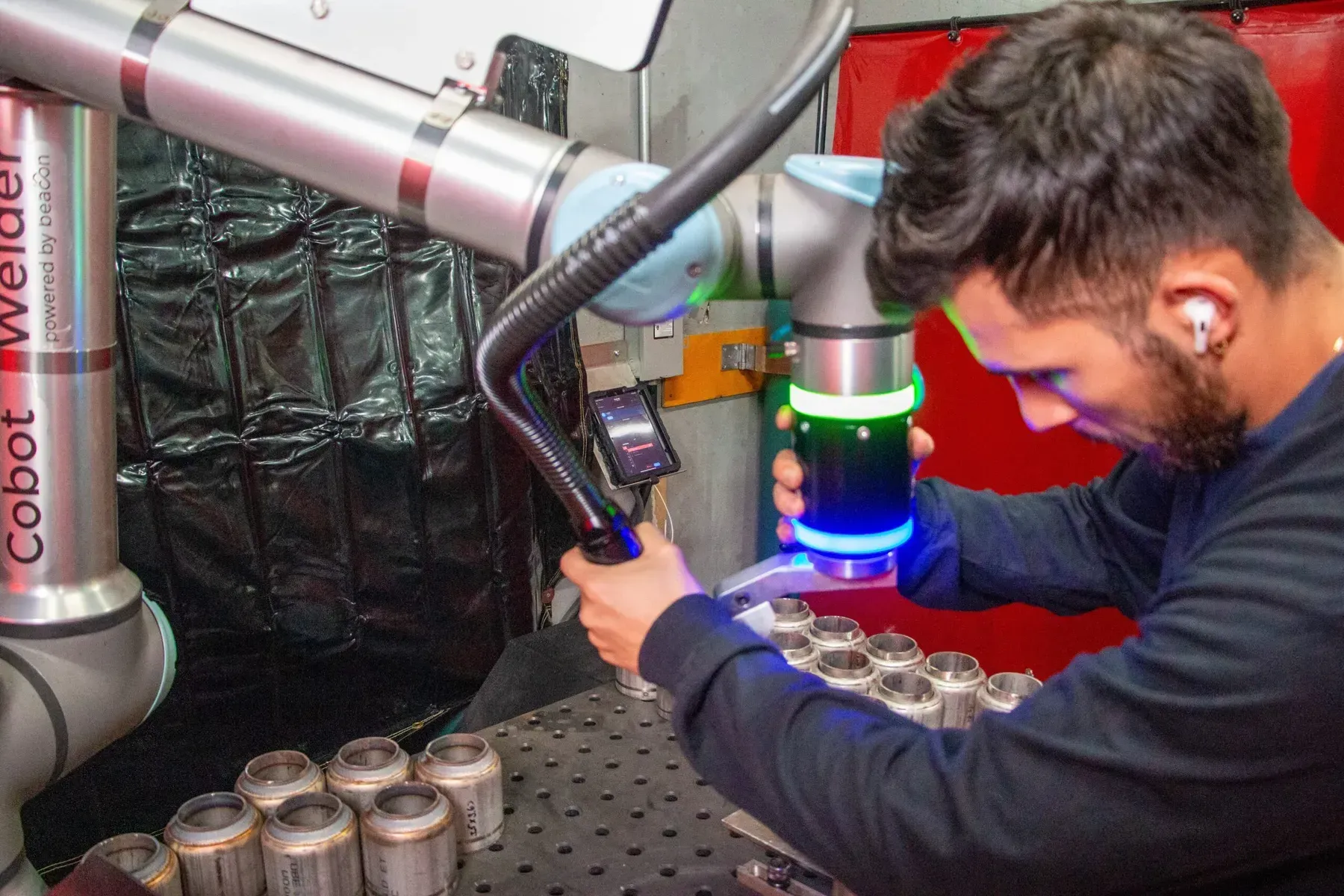 Welder programming a cobot from the Beacon app on the shop floor