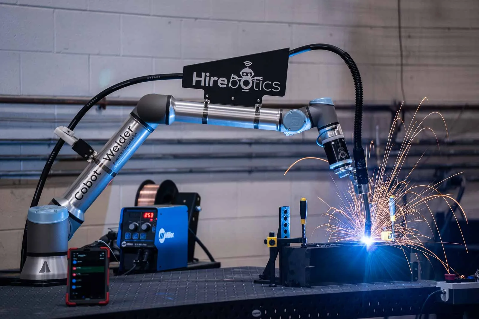 Welder programming a cobot from the Beacon app on the shop floor