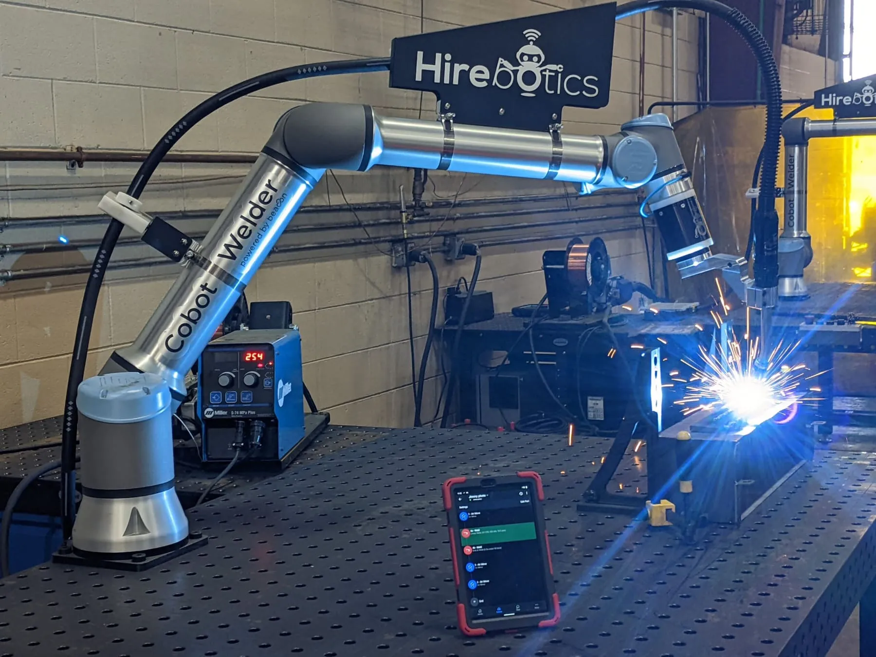 Cobot Welder running a live MIG weld, programmed from the tablet on the table