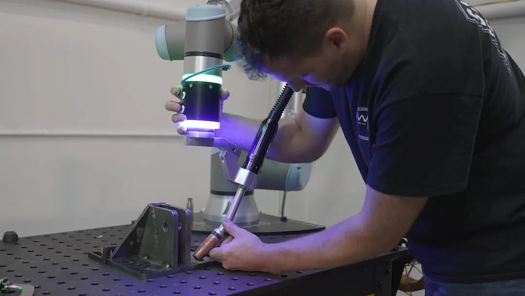 An operator hand-guiding a cobot welder with the Smart Puck