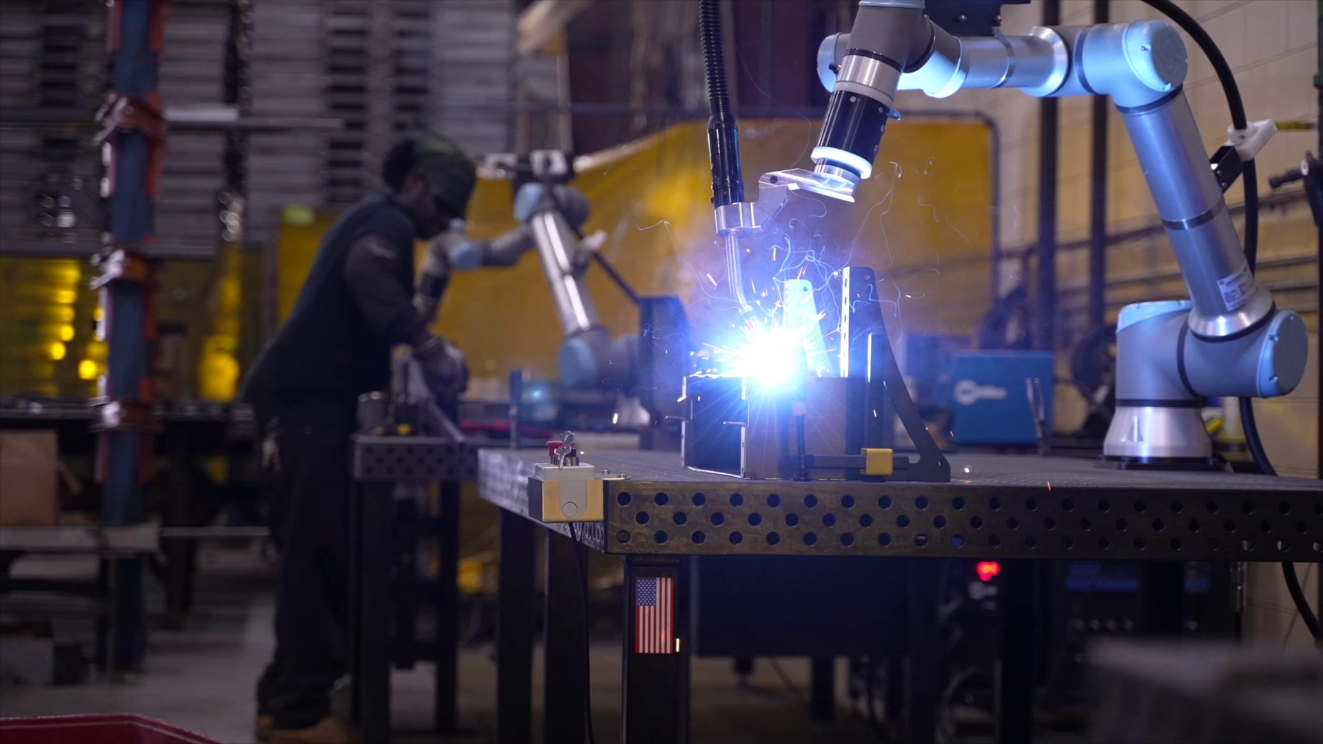 operator-tending-cobot-welder-while-another-welds