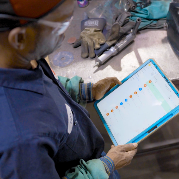 Huncilman lead welder with weld mask next to Hirebotics Cobot Welder